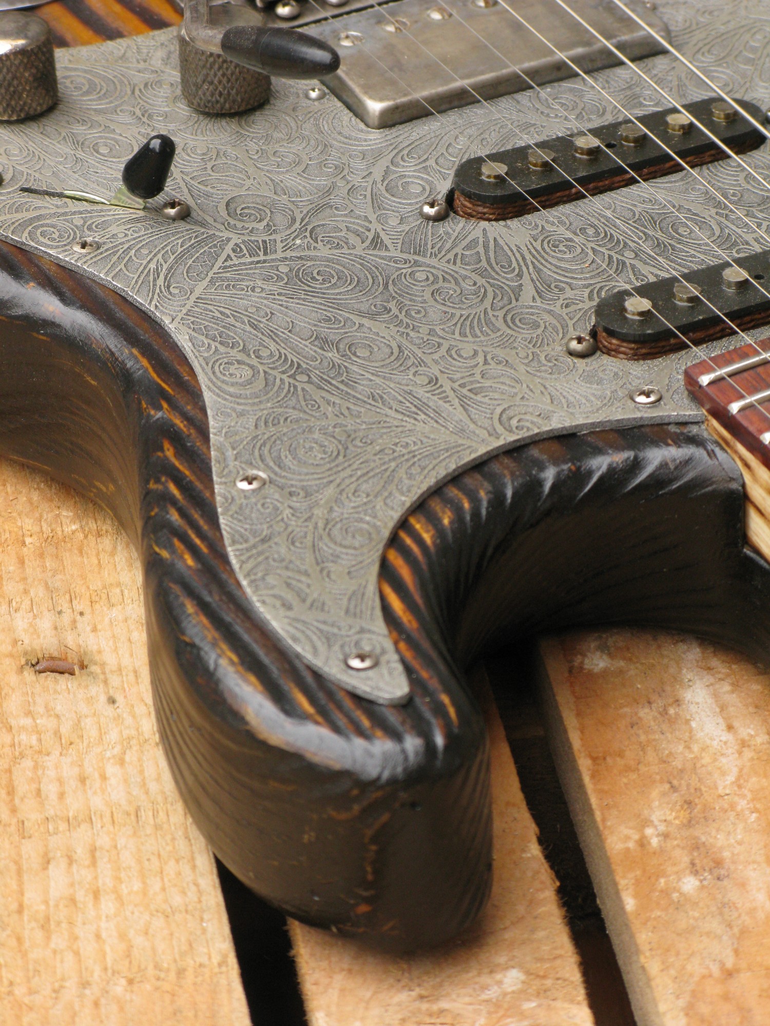 Dettaglio del battipenna inciso di una chitarra elettrica Stratocaster in pino