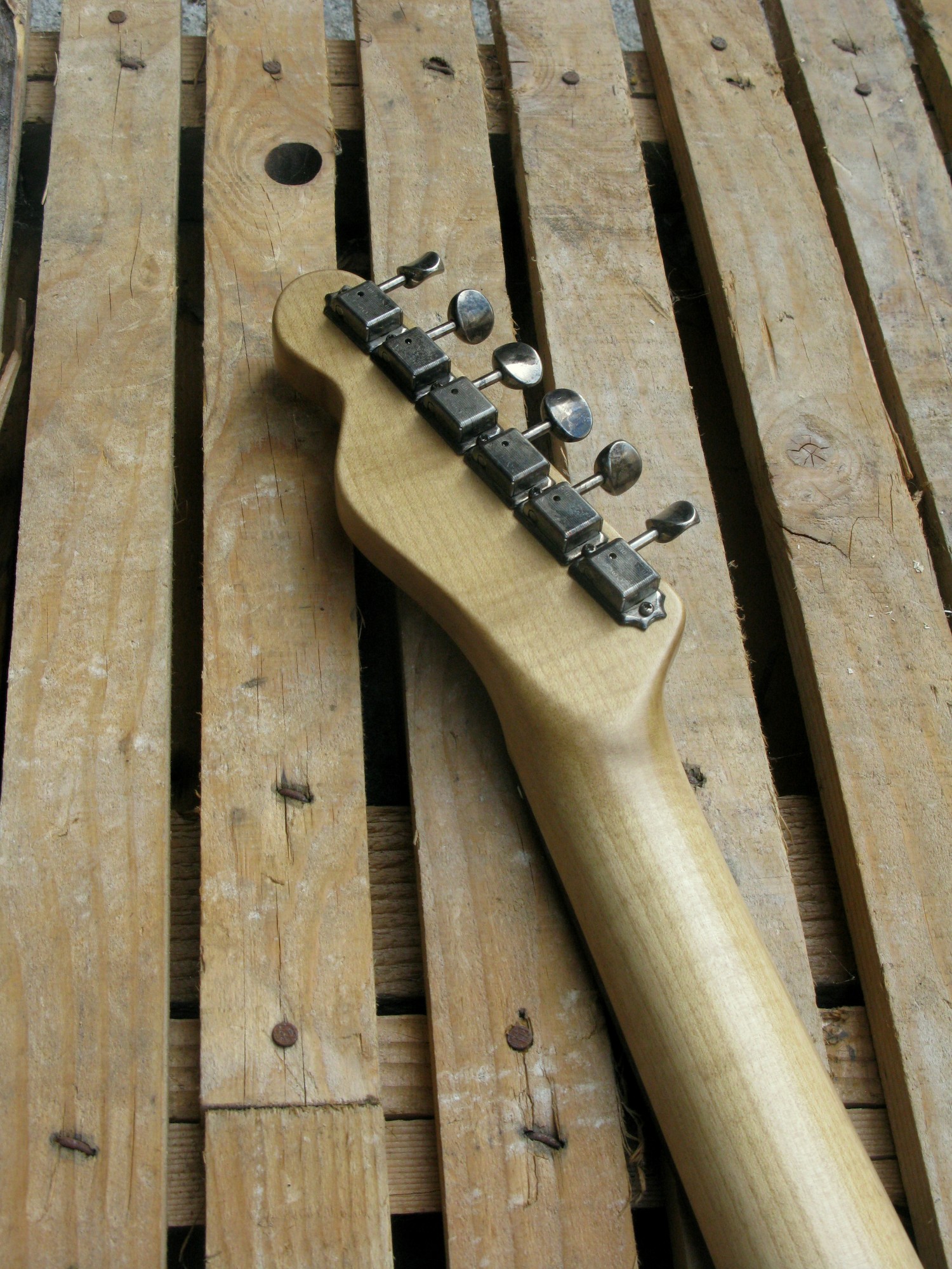 Retro del manico in acero di una chitarra elettrica baritono modello Telecaster con top ricavato da una vecchia cassetta di polvere da sparo